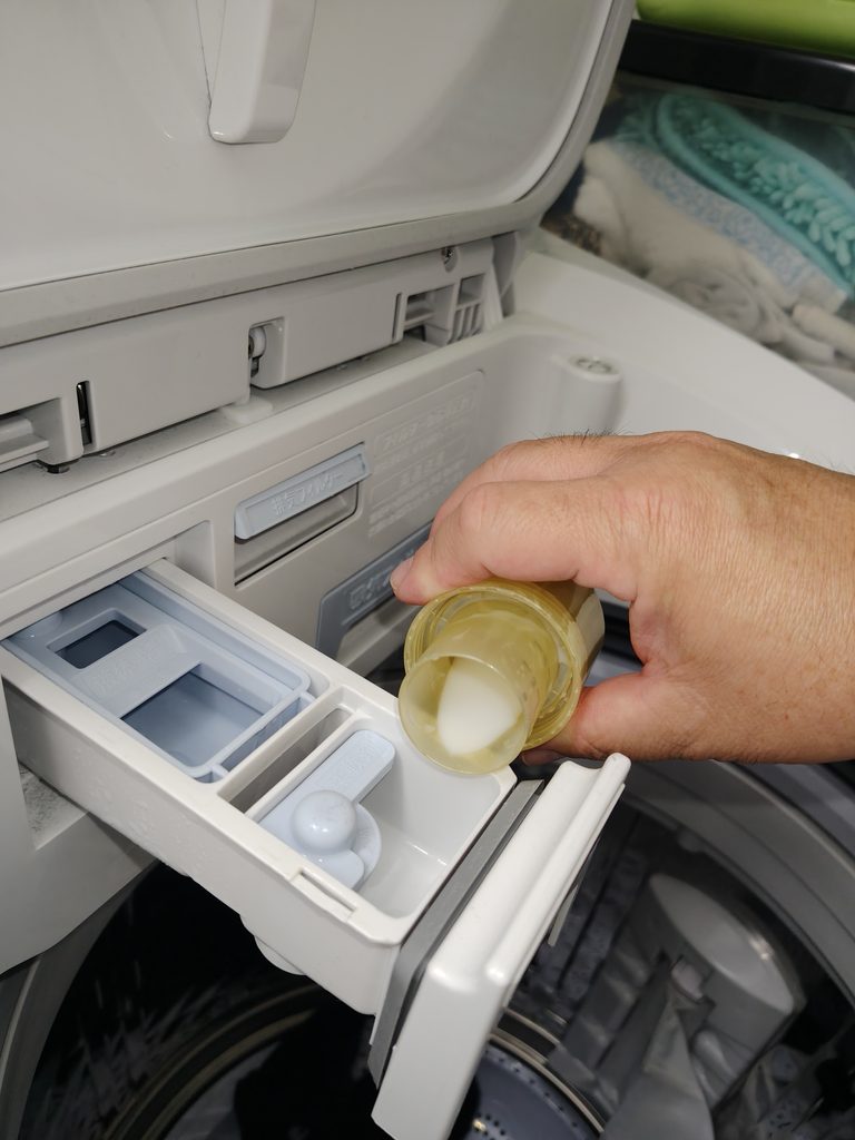 レノアハピネスを柔軟剤投入口に入れているところ